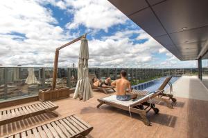 a man sitting on a bed in a pool on a building at 7th Avenue Residence in Curitiba