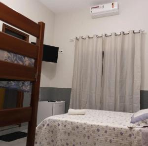 a bedroom with a bed and a window with a curtain at Pousada Gê in Caldas Novas