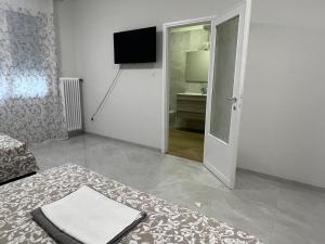 a white living room with a television and a door at Casa Roma rooms&apartments in Padova