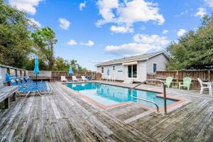 a swimming pool on a deck with chairs and a house at 4720 Summer Ln in Kitty Hawk