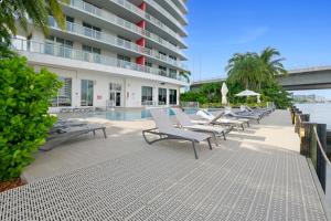 a row of chaise lounge chairs next to a building at Hallandale Sky Water View in Hallandale Beach