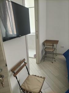 een kamer met een stoel en een televisie aan de muur bij Rooms add e criatur in Napels +4 foto's