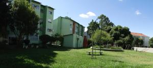a green building with a park in front of it at Apto Familiar Completo, 2 quartos in Porto Alegre