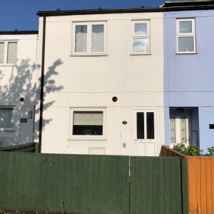 a white house with a fence in front of it at Comfy 2 bedroom house, newly refurbished, self catering, free parking, walking distance to Cheltenham town centre in Cheltenham