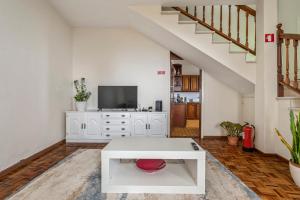 een woonkamer met een witte tafel en een tv bij De Freitas Home in Porto Moniz
