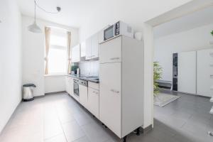 cocina blanca con armarios blancos y microondas en Modern City Apartment in Vienna, en Viena
