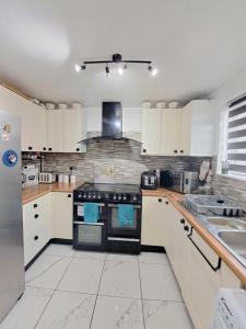 een keuken met witte kasten en een zwarte oven bij Professional Stay Doctors Nurses Trades in Luton