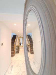 a mirror reflecting a hallway with stairs in a house at Professional Stay Doctors Nurses Trades in Luton