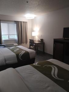 a hotel room with two beds and a desk at Quality Inn & Suites Wilsonville in Wilsonville