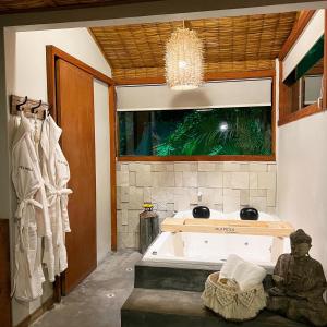 a bathroom with a bath tub and a window at Pousada Vila Piola in Guarda do Embaú