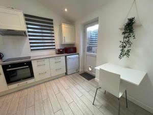 cocina con armarios blancos, mesa y ventana en Modern 3 Bedroom House, Free Parking in Oxford, en Oxford