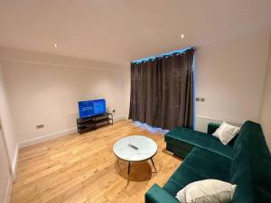 ein Wohnzimmer mit einem grünen Sofa und einem Tisch in der Unterkunft 1 Bed Room Flat Near Central in London