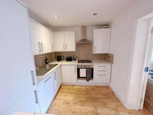uma cozinha com armários brancos e piso em madeira em 1 Bed Room Flat Near Central em Londres