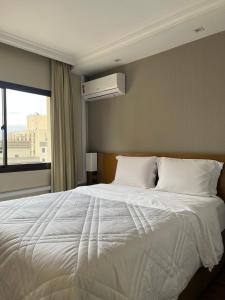 a bedroom with a large white bed with a window at Executivo em Hotel - Vila Olímpia in Sao Paulo