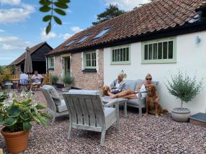 dos personas y dos perros sentados en un patio en Pardlestone Farm Cottages, en Kilve