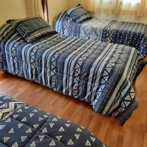 two beds in a room with blue and white sheets at Cabañas L Calafquen in Licán Ray
