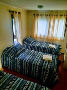 a bedroom with two beds and a window at Cabañas L Calafquen in Licán Ray