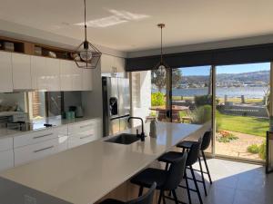 a kitchen with a large white counter and chairs at Merimbula Lake Apartments in Merimbula