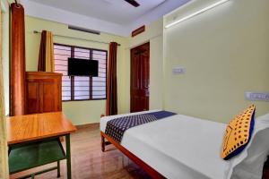 a bedroom with a bed and a desk and a television at SPOT ON 81230 J Square in Trivandrum