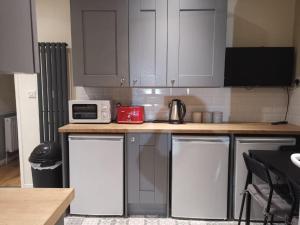 a kitchen with white cabinets and a counter with a microwave at Room Wollanton Park Beeston near East Midlands Conference Centre train station tram stop in Nottingham
