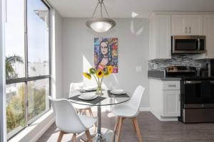 a kitchen with a table and white chairs and a kitchen with a window at Skyline Palms 1-Bedroom with Roof-Top Pool in Los Angeles