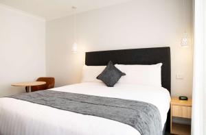 um quarto com uma cama branca e uma cabeceira preta em Econo Lodge Mildura em Mildura