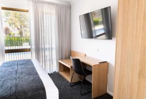 um quarto de hotel com uma cama, uma secretária e uma televisão em Econo Lodge Mildura em Mildura