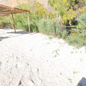 a picnic shelter on a sandy beach next to a river at CAMPING GANIMEDES in Paihuano