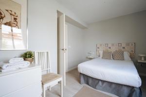 a white bedroom with a bed and a window at Suite Batihojas in Seville