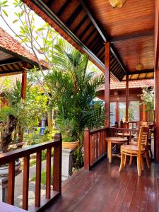une terrasse avec tables et chaises sur une terrasse en bois dans l'établissement Wait Garden Cottage, à Nusa Penida