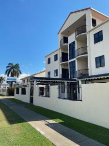 a white building with balconies and a palm tree at City Ville Apartments and Motel in Rockhampton