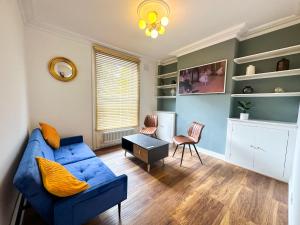 Kennington retreat with garden + king bed في لندن: غرفة معيشة مع أريكة زرقاء وطاولة