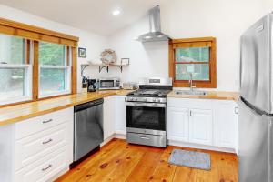 eine Küche mit weißen Schränken und Küchengeräten aus Edelstahl in der Unterkunft Long Island Road Abode in Moultonborough