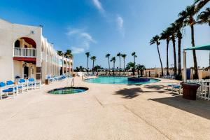 a resort with a pool and chairs and palm trees at Long Island Village 502 Clam in Port Isabel