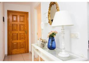 a blue vase with flowers on a table with a lamp at Perchel Sport in Las Palmas de Gran Canaria +26 photos
