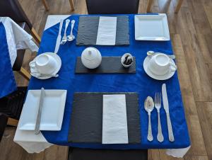 une table bleue avec des ustensiles en argent sur un chiffon de table bleu dans l'établissement The Senarth, à Llandudno