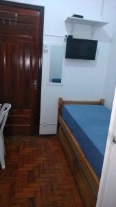 a small bedroom with a bed and a wooden door at Quartos no centro de Itu - Hospedagem Elizabeth in Itu
