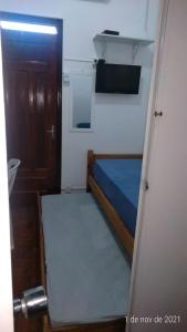 um pequeno quarto com uma cama e uma porta em Quartos no centro de Itu - Hospedagem Elizabeth em Itu