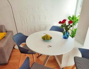 un tavolo bianco con una ciotola di uva e un vaso di fiori di Have a nice stay in Rome a Roma