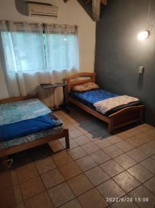 a room with two beds and a table with a window at Casa de 4 habitaciones con piscina en barrio cerrado a 5 minutos del Aeropuerto Internacional in Luque