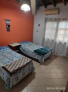 2 Betten in einem Zimmer mit orangefarbenen Wänden und Fenstern in der Unterkunft Casa de 4 habitaciones con piscina en barrio cerrado a 5 minutos del Aeropuerto Internacional in Luque