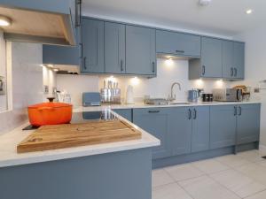 a kitchen with blue cabinets and a wooden cutting board at Wellington Cottage in Ely