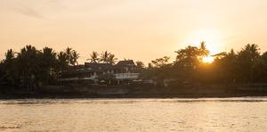 een huis op het strand met de zonsondergang op de achtergrond bij Bombora Medewi in Pulukan