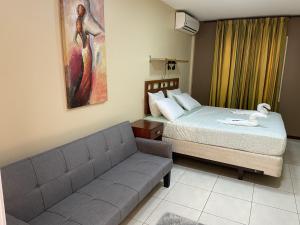 a bedroom with a couch and a bed and a painting at 101 Suites in Paramaribo