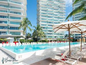 a swimming pool with chairs and an umbrella and some buildings at Icon Vallarta Beach front By Bamboo Skylife in Puerto Vallarta