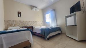 a room with two beds and a flat screen tv at Hotel Raio do Sol in Ibicoara