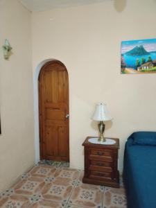 a bedroom with a door and a table with a lamp at Hotel Nolasco in Antigua Guatemala