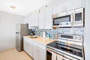 a kitchen with white cabinets and a stainless steel refrigerator at Waikiki condo - ocean views, lanai & beach access in Honolulu