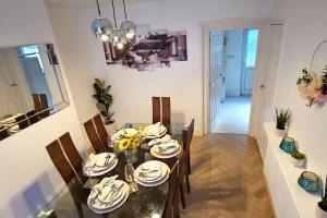 een eetkamer met een glazen tafel en stoelen bij Alfred House in Ripley