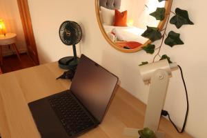 ordenador portátil con escritorio y ventilador en Cosy home in London en Londres